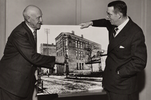 65 Years of Service — John Thompson & Raymond E. Olson (1951) Thermometer maker John Thompson (left), who served 65 continuous years (1884–1949), points out his original workbench to Vice President Raymond E. Olson on an archival print of the pre-1906 Taylor Brothers factory. (Centennial press release, March 1951).