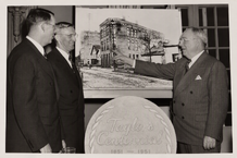 Reflecting on Early Days VP Raymond E. Olson (left) with two unidentified colleagues beside the 1851–1951 Centennial seal and an early Taylor Brothers factory photograph.