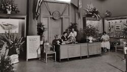 Information & Reception Desk Staff greeting guests in the main lobby beside historic instrument cases and milestone placards.
