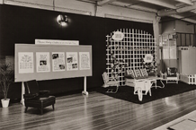 Centennial Garden & Policy Exhibit Staged garden trellis patio (1851–1951) and bulletin display highlighting employee clubs, tenure statistics, and company policy.